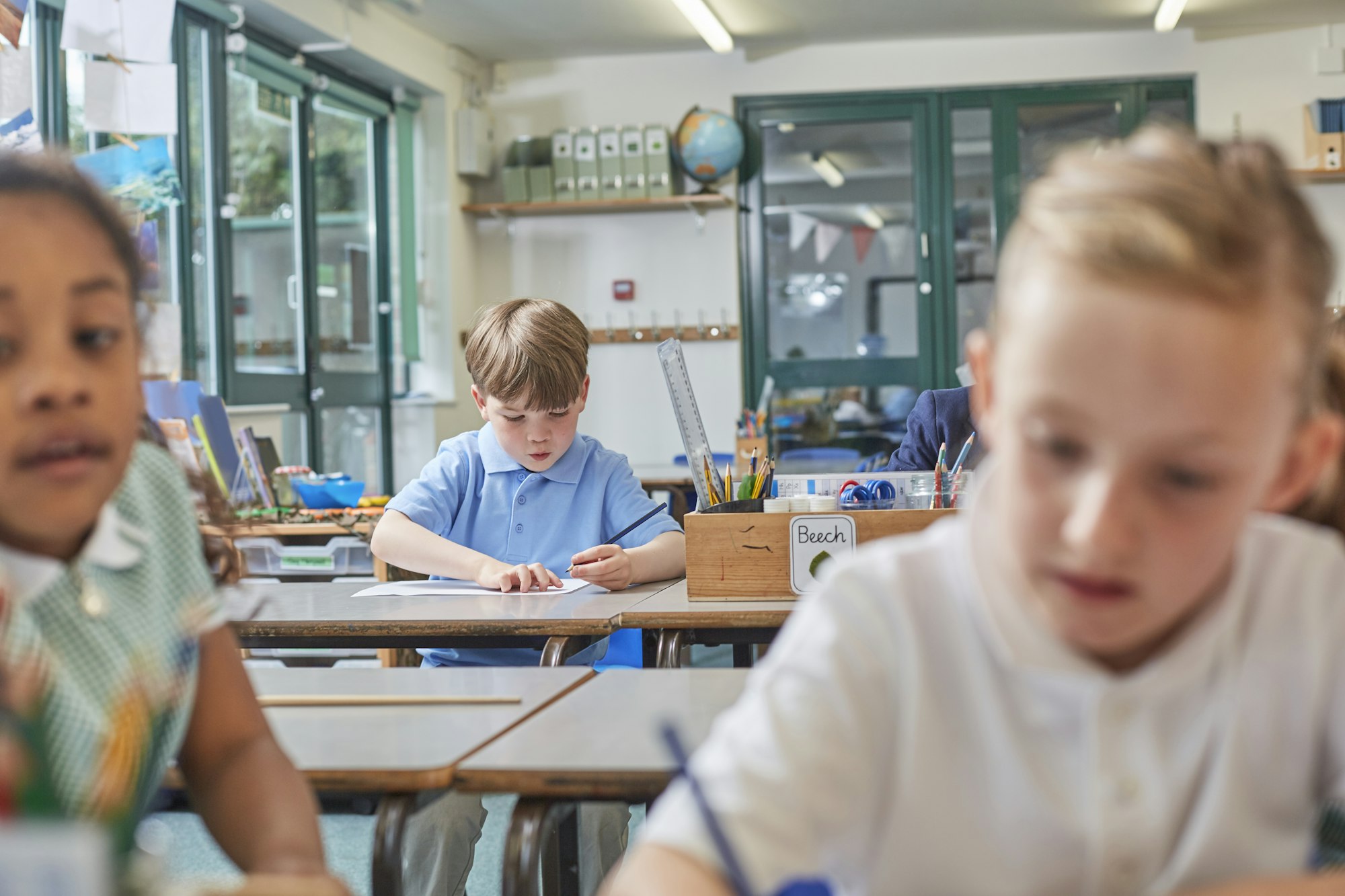 Primary schoolboy and girls doing schoolwork at classroom desks