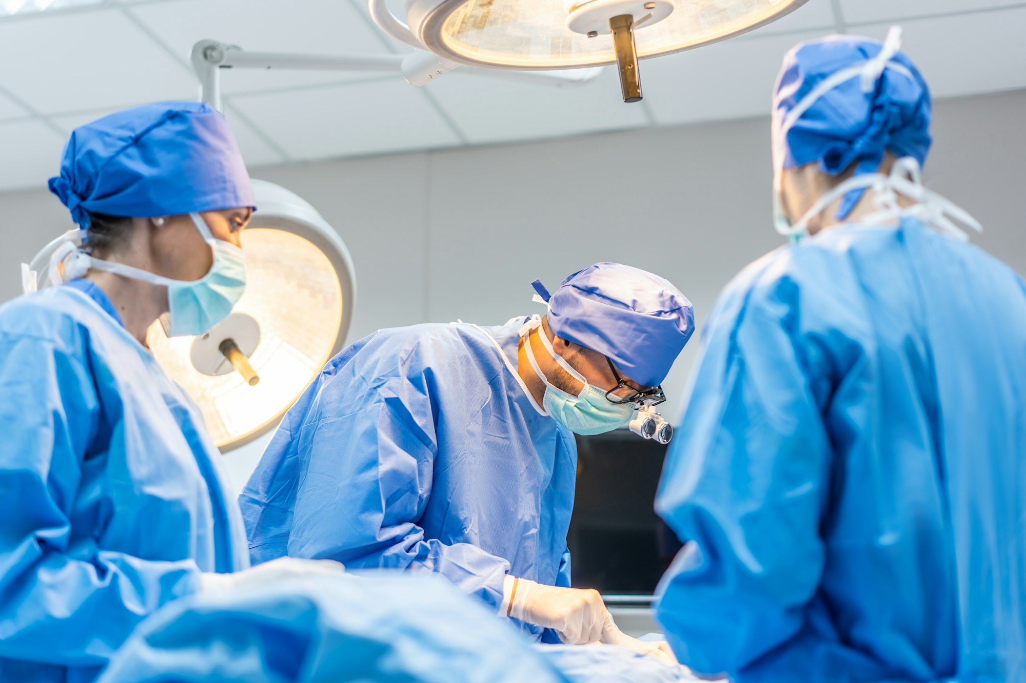 Professional doctors performing surgical operation in operating room.